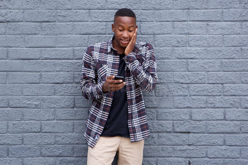 Surprised young african guy looking at cell phone