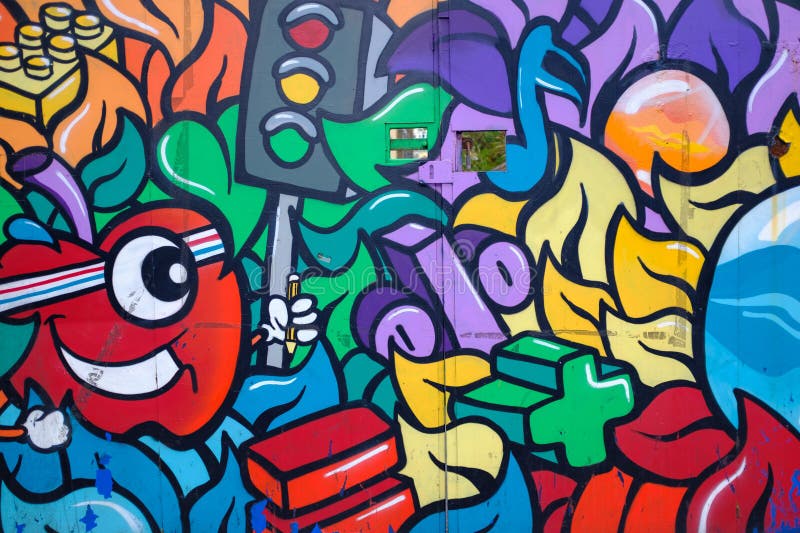 Surrounding elements include abstract shapes, vibrant colours, LEGO-like blocks, and a green plus sign. The composition is lively, dynamic, and full of energy, with a variety of swirling and intertwining forms in shades of purple, blue, orange, and yellow. The artwork covers a flat surface, creating an engaging visual tapestry.