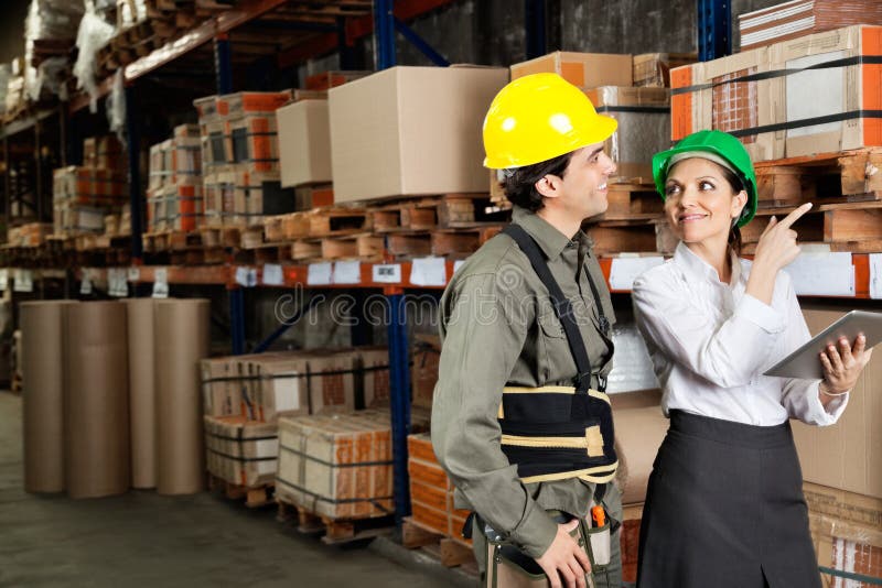 Female supervisor with foreman pointing at stock on shelves in warehouse. Female supervisor with foreman pointing at stock on shelves in warehouse