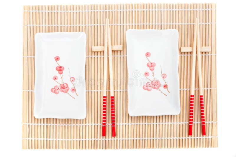 Sushi plates and chopsticks on bamboo mat