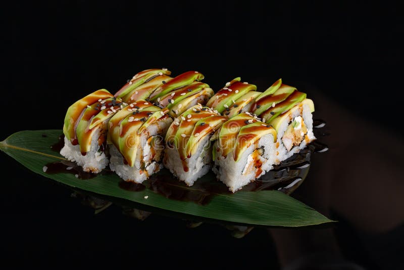 Sushi rolls japanese food over black background. Sushi roll with salmon, tofu, vegetables and avocado closeup. Japan restaurant