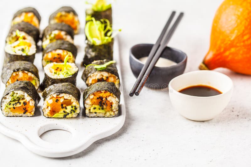 Sushirollen des strengen Vegetariers mit Kürbis, Naturreis und Avocado stockfotografie Sushirollen des strengen Vegetariers mit Kürbis, Naturreis und Avocado stockfotografie