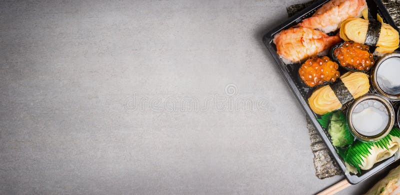 Sushisatz im Transportkasten auf grauem Steinhintergrund, Draufsicht, Platz für Text lizenzfreie stockbilder