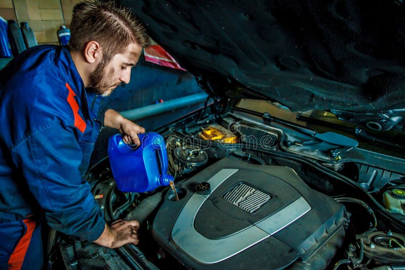 Sustitución y vertido de aceite mecánico en el motor en la estación de servicio de reparación de mantenimiento fotografía de archivo libre de regalías Sustitución y vertido de aceite mecánico en el motor en la estación de servicio de reparación de mantenimiento fotografía de archivo libre de regalías