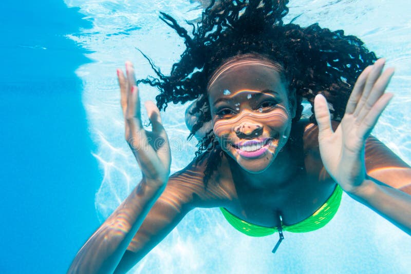 Svart flickadykning i simbassäng på semestern