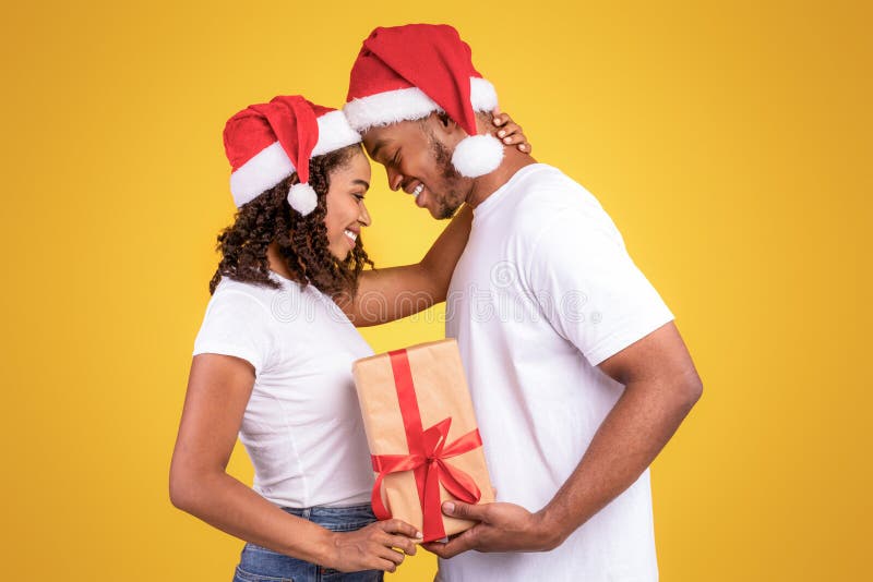 Svart par Huggande Holding-julklapp stående på gul bakgrund arkivfoton