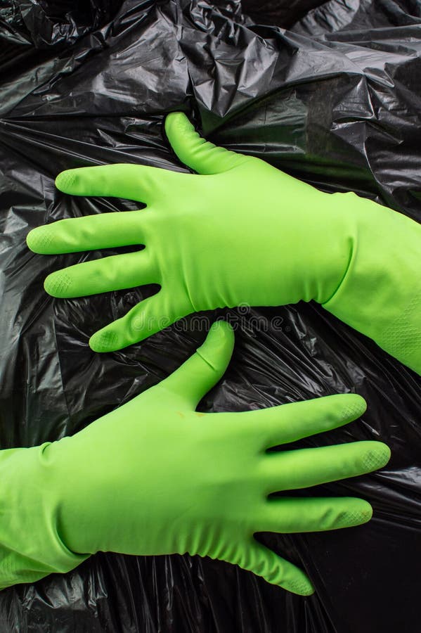 Svart plastpåsstruktur i händerna i grön handskar bakgrund Abstrakt illustration av rengöring och sortering av skräp royaltyfria foton