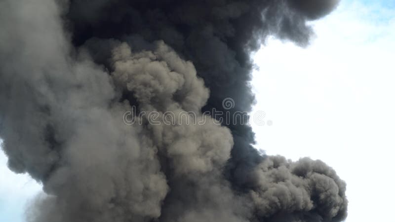 Black smoke rises into the sky. A big chemical fire at a factory building. Thick black smoke covers the sky. 4k. Black smoke rises into the sky. A big chemical fire at a factory building. Thick black smoke covers the sky. 4k