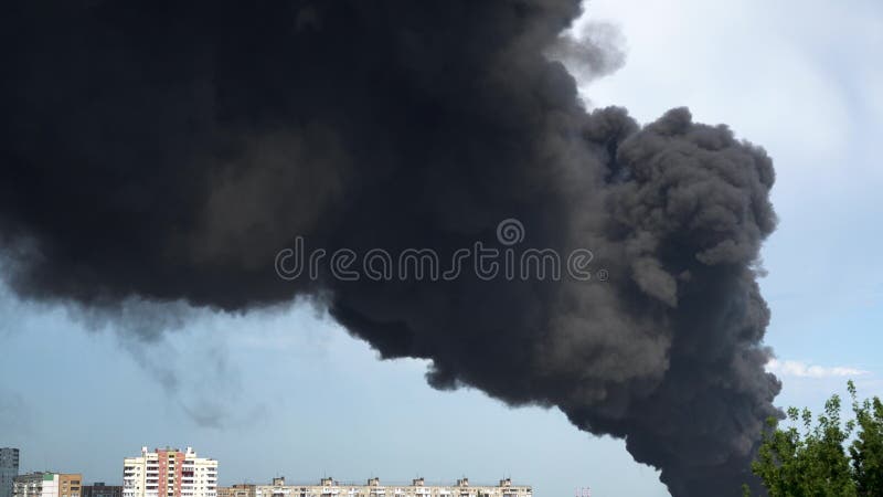 Black smoke rises above the buildings. A big chemical fire at a factory building. Thick black smoke covers the sky. 4k. Black smoke rises above the buildings. A big chemical fire at a factory building. Thick black smoke covers the sky. 4k