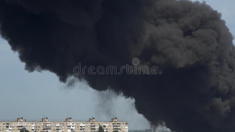 Black smoke rises above the buildings. A big chemical fire at a factory building. Thick black smoke covers the sky. 4k. Black smoke rises above the buildings. A big chemical fire at a factory building. Thick black smoke covers the sky. 4k