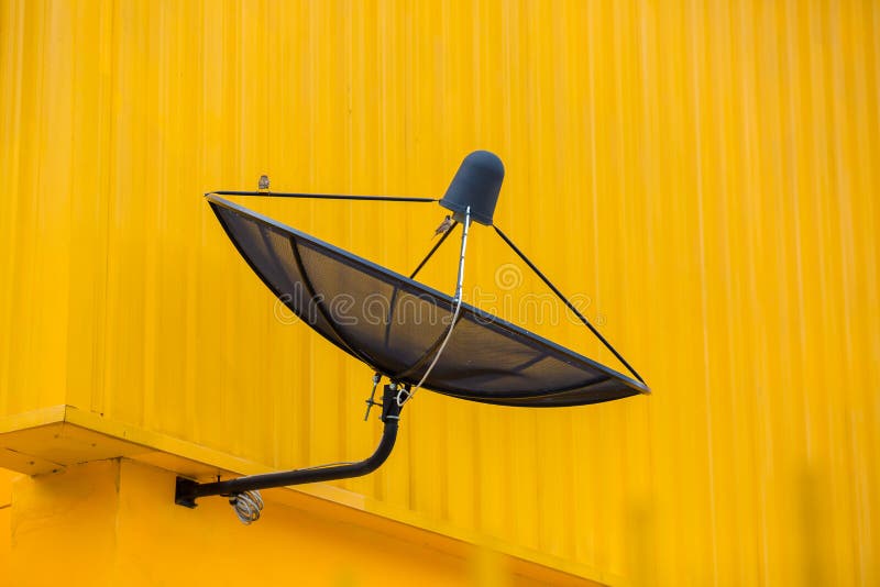 Svart satellitkommunikationsskiva på gul vägg royaltyfria foton Svart satellitkommunikationsskiva på gul vägg royaltyfria foton