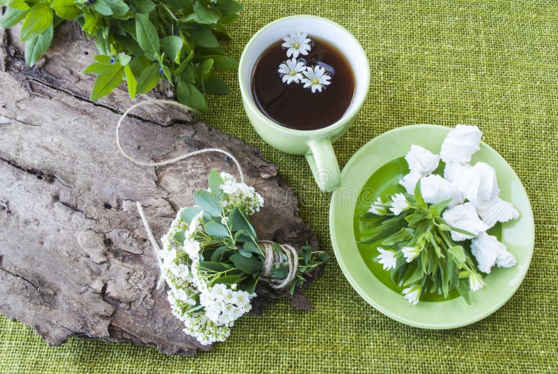 Svart te på en bakgrund av gröna textiler, en bukett av blommor arkivbild Svart te på en bakgrund av gröna textiler, en bukett av blommor arkivbild
