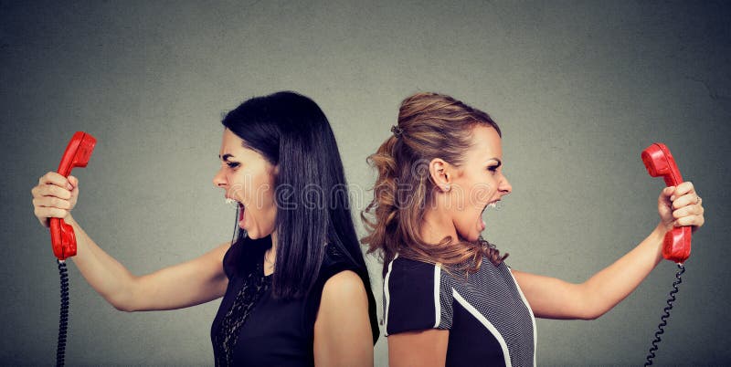 Communication concept. Two angry women screaming at each other over the phone isolated on gray background. Communication concept. Two angry women screaming at each other over the phone isolated on gray background.
