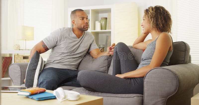 Svarta par som har en konversation i deras vardagsrum