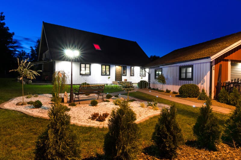 Svenskt villahus med den moderna trädgården på nattetid royaltyfri bild Svenskt villahus med den moderna trädgården på nattetid royaltyfri bild
