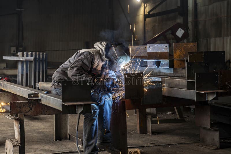 Welding with sparks by Process fluxed cored arc welding ,Industrial steel welder part in factory welder Industrial automotive part in factory. Welding with sparks by Process fluxed cored arc welding ,Industrial steel welder part in factory welder Industrial automotive part in factory