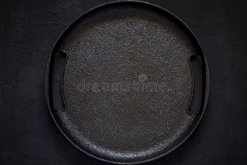 Svuoti il piatto rustico del ghisa su un fondo nero Spirito di vista superiore immagini stock libere da diritti Svuoti il piatto rustico del ghisa su un fondo nero Spirito di vista superiore immagini stock libere da diritti