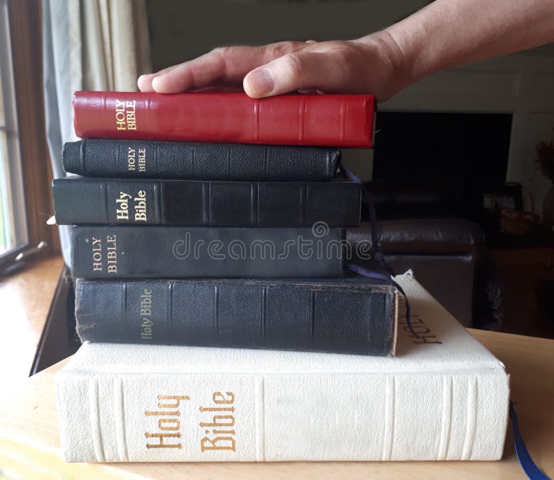 A hand on top of a stack of bibles is ready to swear the truth. A hand on top of a stack of bibles is ready to swear the truth