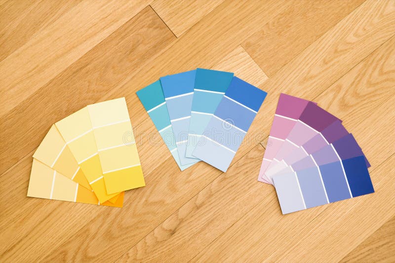 Paint color swatches grouped together by color on wood floor. Paint color swatches grouped together by color on wood floor.