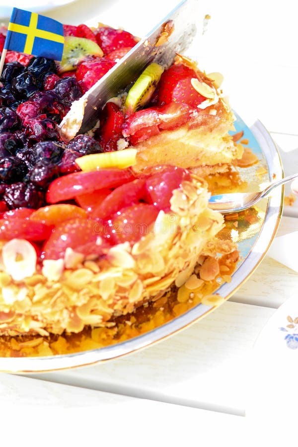 Swedish summer cake with cream, strawberries and fruit, garnished almonds around in thin slices. sun and copy space. Swedish summer cake with cream, strawberries and fruit, garnished almonds around in thin slices. sun and copy space