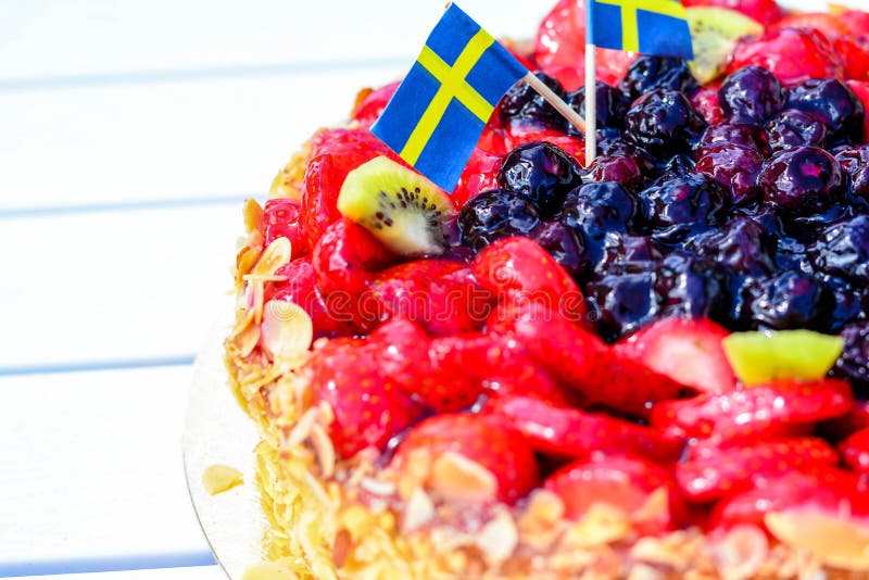 Swedish summer cake with cream, strawberries and fruit, garnished almonds around in thin slices. sun and copy space. Swedish summer cake with cream, strawberries and fruit, garnished almonds around in thin slices. sun and copy space