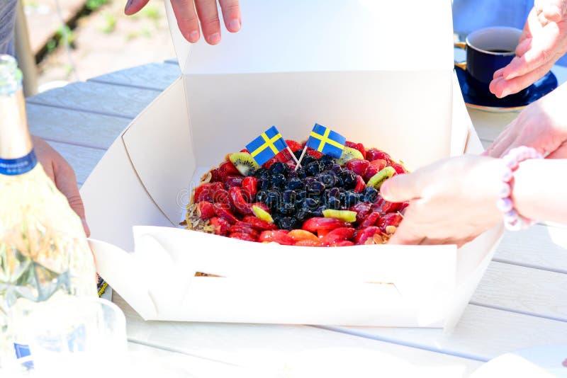 Swedish summer cake with cream, strawberries and fruit, garnished almonds around in thin slices. sun and copy space and swedish flags its midsummer. Swedish summer cake with cream, strawberries and fruit, garnished almonds around in thin slices. sun and copy space and swedish flags its midsummer