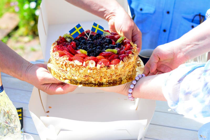 Swedish summer cake with cream, strawberries and fruit, garnished almonds around in thin slices. sun and copy space and swedish flags. Swedish summer cake with cream, strawberries and fruit, garnished almonds around in thin slices. sun and copy space and swedish flags