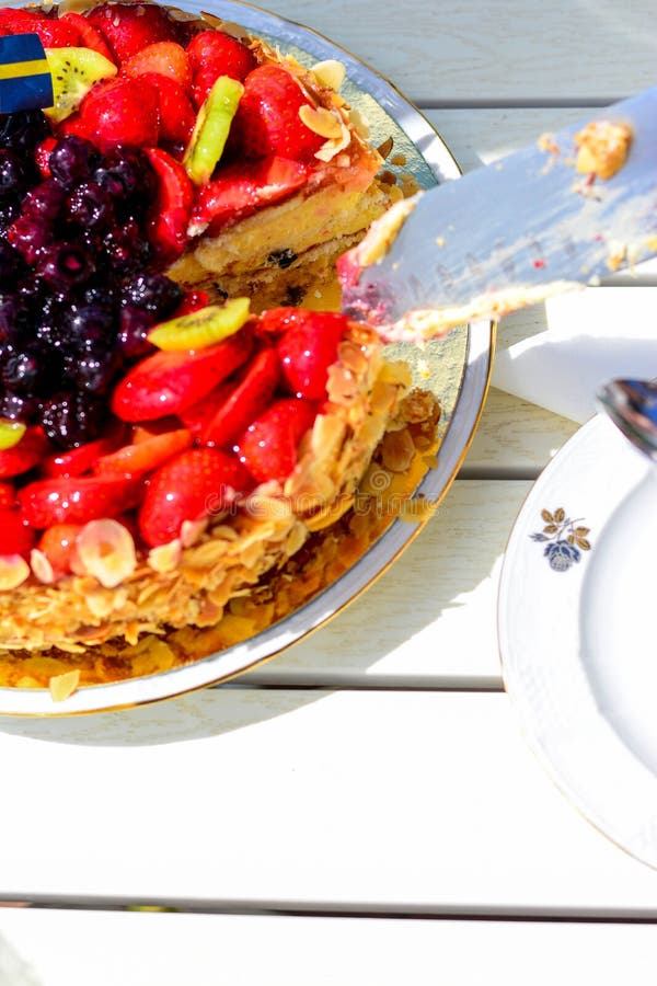 Swedish summer cake with cream, strawberries and fruit, garnished almonds around in thin slices. sun and copy space. Swedish summer cake with cream, strawberries and fruit, garnished almonds around in thin slices. sun and copy space