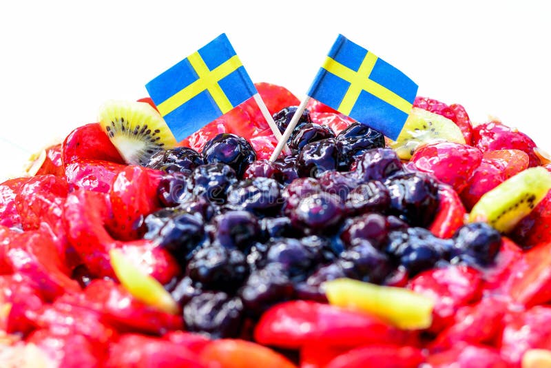 Swedish summer cake with cream, strawberries and fruit, garnished almonds around in thin slices. sun and copy space and swedish flags. Swedish summer cake with cream, strawberries and fruit, garnished almonds around in thin slices. sun and copy space and swedish flags