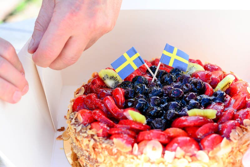 Swedish summer cake with cream, strawberries and fruit, garnished almonds around in thin slices. sun and copy space and swedish flags. Swedish summer cake with cream, strawberries and fruit, garnished almonds around in thin slices. sun and copy space and swedish flags