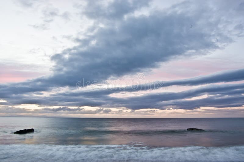 Wide striking wispy clouds at sunrise in Scotland with a dark blue sea in which are two World War 2 defence bunkers - Forres Scotland. Wide striking wispy clouds at sunrise in Scotland with a dark blue sea in which are two World War 2 defence bunkers - Forres Scotland