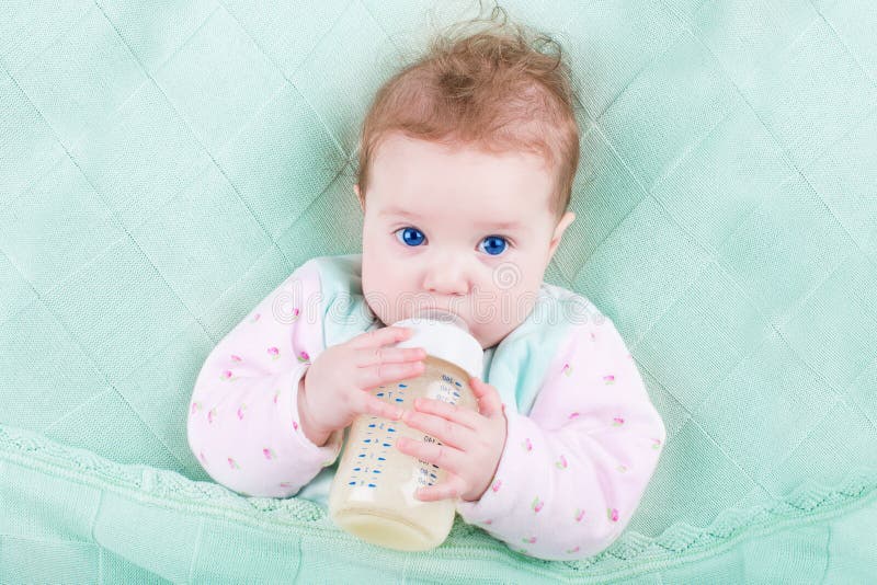 Sweet baby with big blue eyes drinking milk