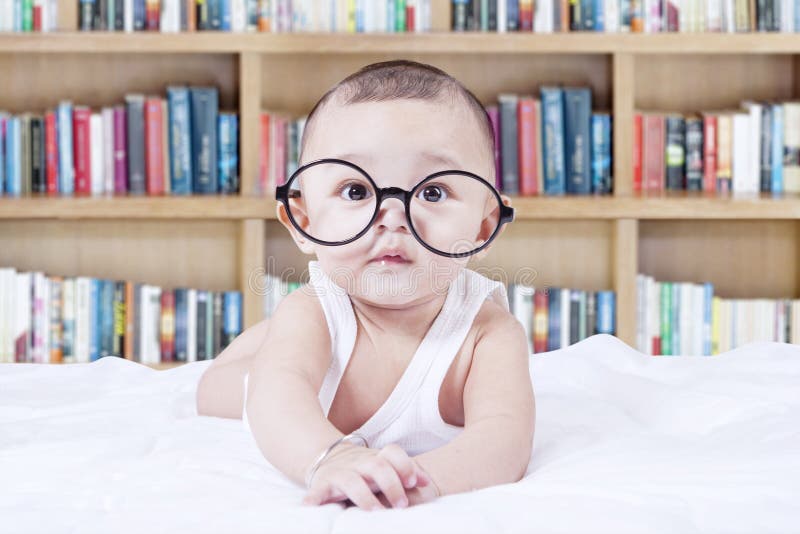 Sweet Baby With Glasses And A Bookcase Background Stock Photo