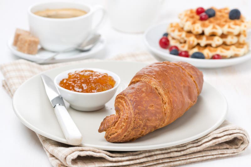 Sweet breakfast with croissant, jam, waffles, berries and coffee