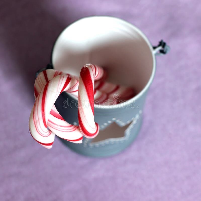 Sweet Christmas candy canes in a light gray cup with a star hole, retro concept