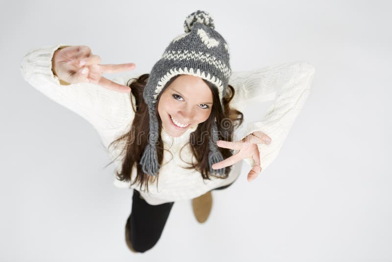 Sweet girl in cool winter clothing laughing, making victory sign