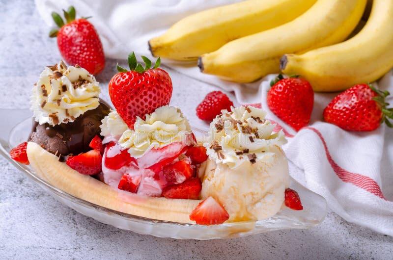 Sweet homemade banana split sundae with chocolate vanilla and strawberry ice cream on glass bowl, decorated topping fresh