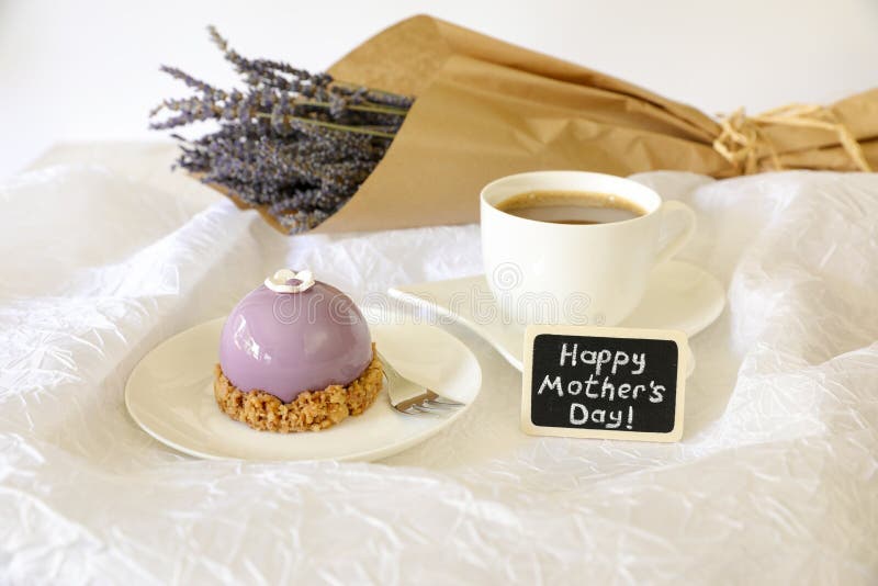 Sweet morning breakfast time concept, beautiful violet cake, cup of coffee near plate with the note Happy Mother`s Day