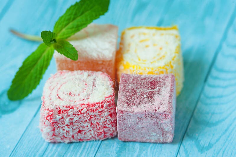 Sweet pieces of turkish delight on blue background With a leaf of mint