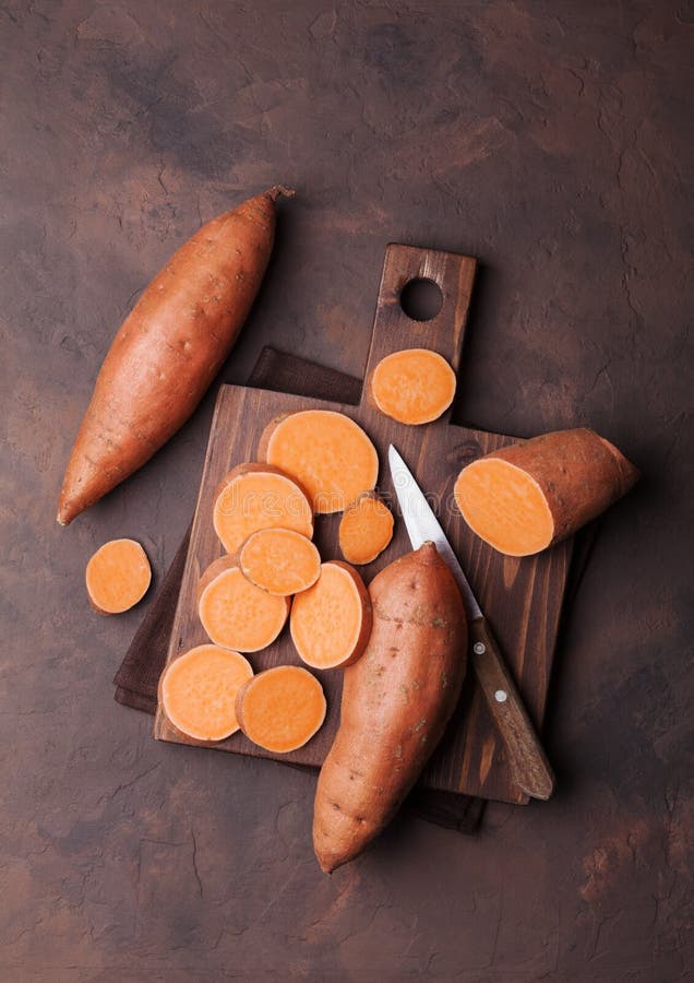 Sweet potato on wooden kitchen board from above.