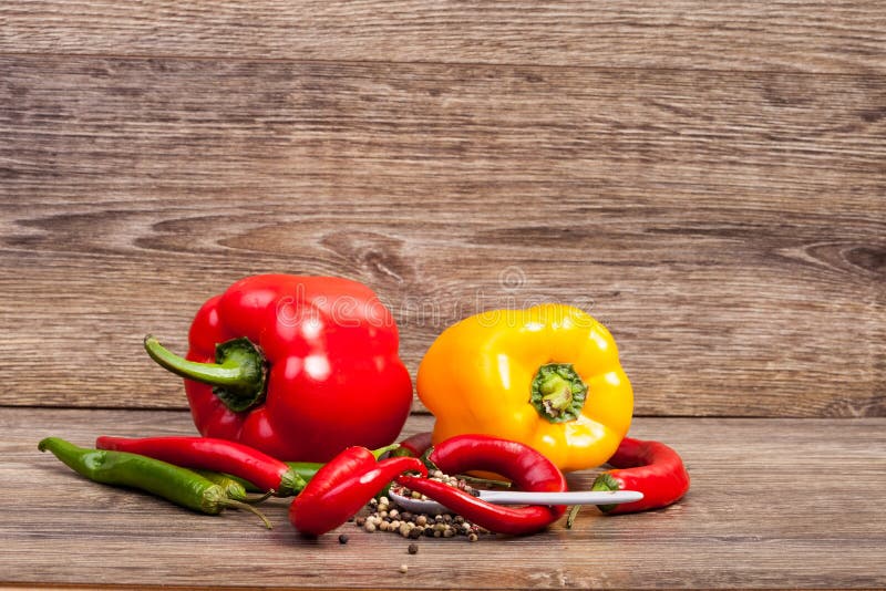 Sweet and spicy peppers on wooden background