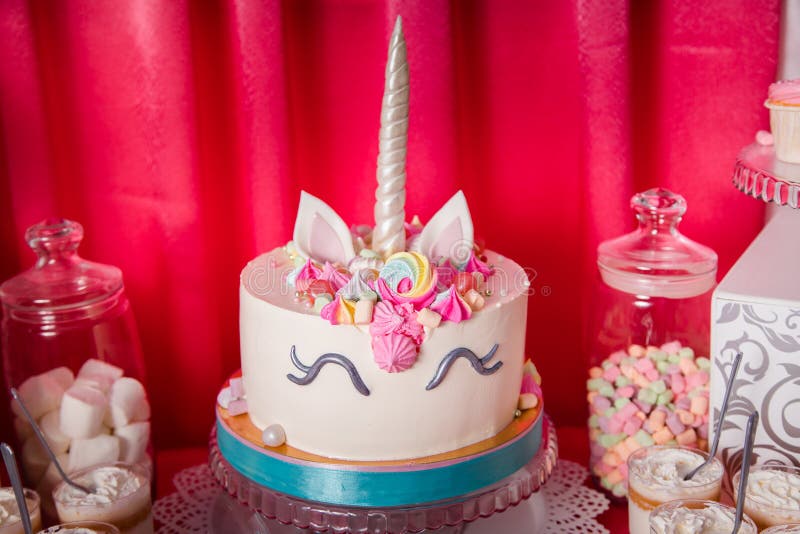 Sweet table and big unicorn cake for baby girl first birthday. Candy bar with a lot of different candies and sweet cakes.