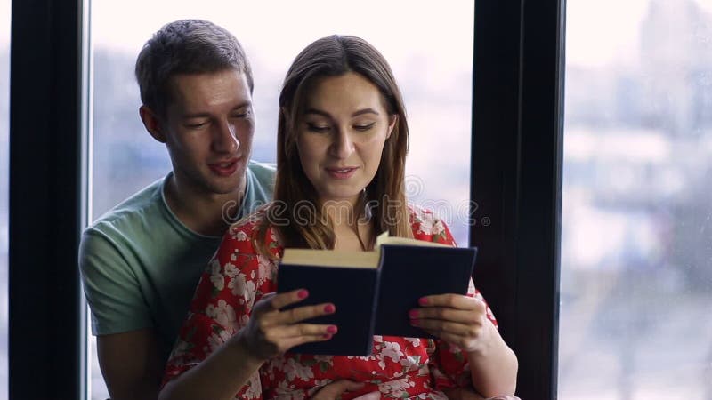 Sweet young couple reading a book together at home