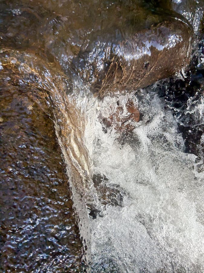 Swift flow of clear river water with large rocks against a backdrop of beautiful green trees royalty free stock photography