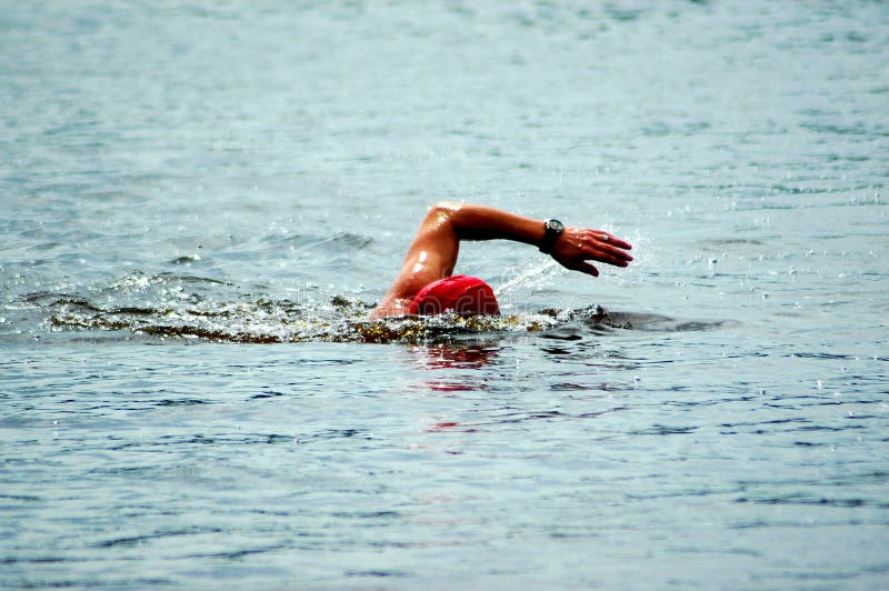 A white arm of a caucasian swimmer athlete swimming in the lake