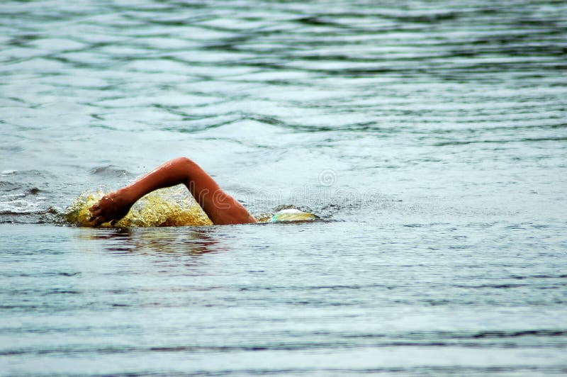 A white arm of a caucasian swimmer athlete swimming in the lake