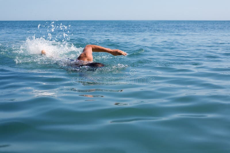 Young swimmer floating crawl into the sea.