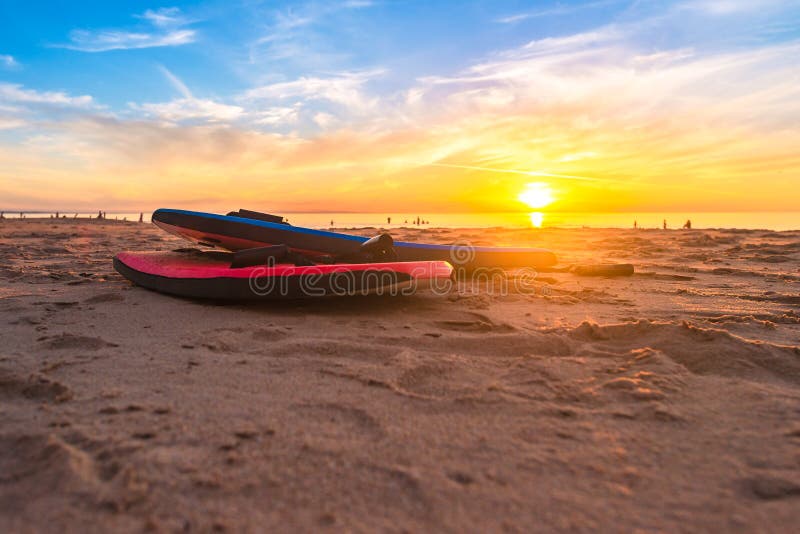 Swimming bodyboards on the beach at sunset