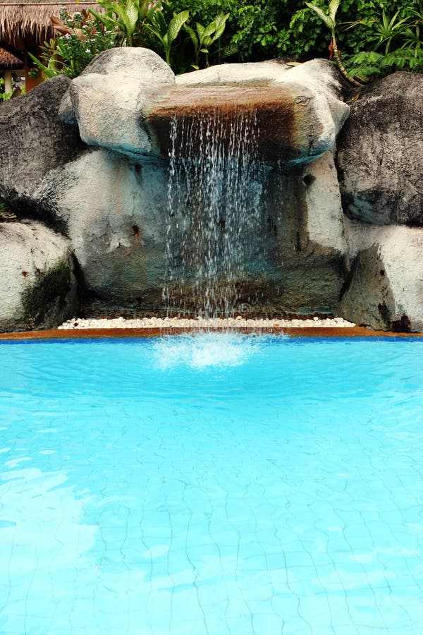 Man-made waterfall flowing into a swimming pool at a tropical spa resort in Phuket, Thailand - travel and tourism. Man made waterfall stock images, royalty-free photos and pictures