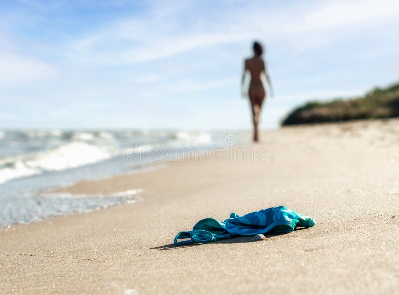 Naked Public Beach Vedeo - Swimsuit in the Sand on the Beach Near the Sea Surf on the Background of a  Naked Female Figure and Blue Sky Stock Image - Image of girl, ocean:  129900691